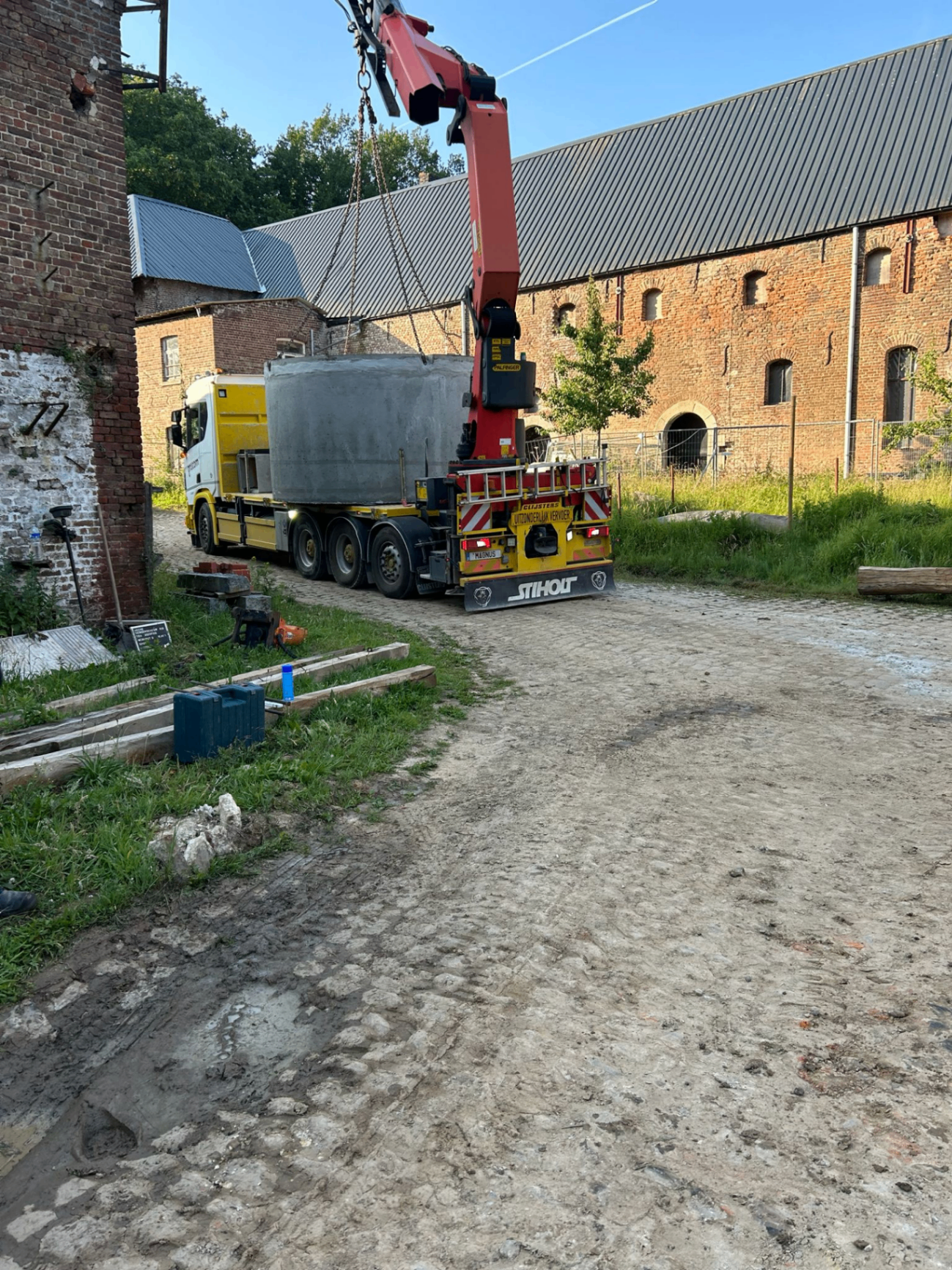 Plaatsing van een grote betonnen regenwaterput met kraanwagen bij een andere historische site
