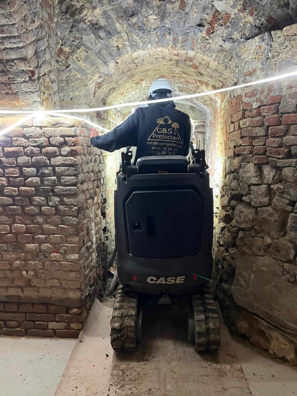 CASE minigraver in een smal bakstenen gewelf onder het Kasteel van Heers